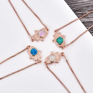 Detail of rose gold Hamsa necklaces with colorful opal stones and diamond edges