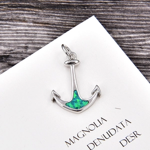 Macro shot of silver anchor pendant featuring vivid green opal inlay and polished metal details
