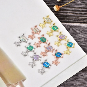 Macro detail of turtle charms set featuring vibrant opal stone inlay and mixed metal finishes
