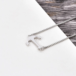 Detailed view of silver anchor pendant with box chain on a vintage wooden surface