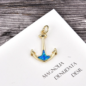 Macro detail of nautical anchor pendant with gold finish and vibrant blue opal stone