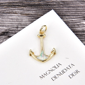 Macro detail of a gold plated anchor pendant with iridescent opal and sparkling zircon inlay