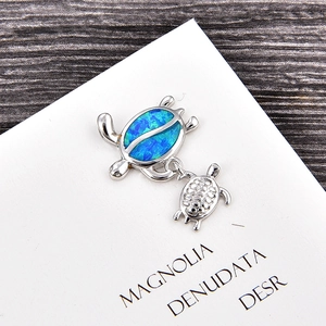 Macro view of silver turtle pendant with blue opal shell on a white decorative card