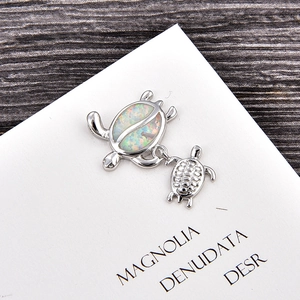Macro shot of silver turtle pendant featuring iridescent opal stone and shell details