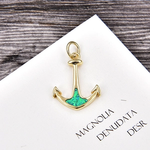 Detail of a gold anchor pendant with a green opal inlay on a white jewelry display card