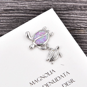 Detail of a turtle pendant featuring pink opal inlay and small silver turtle charm