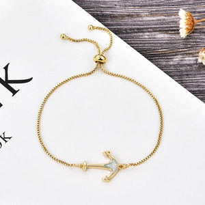 Detail of a gold-plated anchor bracelet with opal inlay and adjustable box chain
