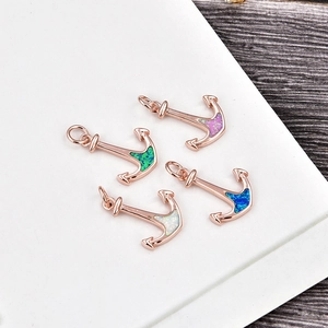 Macro detail of anchor pendants in rose gold with colorful opal inlays and secure rings
