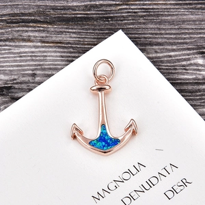 Macro detail of rose gold anchor pendant with vibrant blue opal inlay and copper base