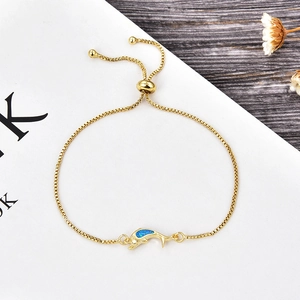 Close-up of golden box chain bracelet with blue opal dolphin charm and adjustable slider