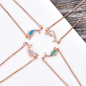 Macro shot of dolphin pendants with colorful opal inlay in rose gold plated finishes