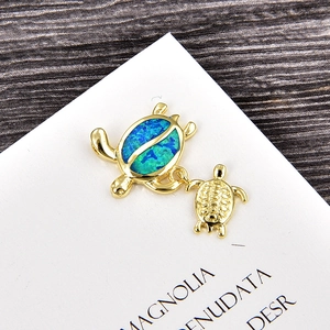 Detail of mother and child sea turtle pendant with blue-green opal inlay and gold finish