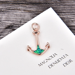 Detail view of a rose gold anchor pendant featuring blue-green opal and zircon inlay