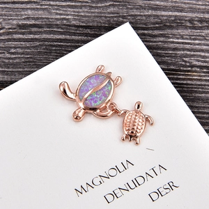 Close-up of rose gold turtle pendant with vibrant purple opal stone on wood background