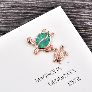 Detail of rose gold turtle pendant featuring vibrant green opal inlay and polished metal finish