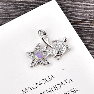 Macro view of a silver turtle and starfish pendant with purple opal inlay and micro-zircon