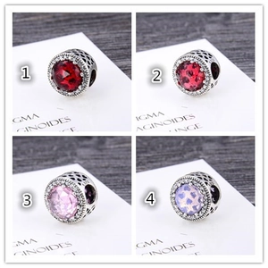 Macro view of S925 silver charms with colorful gemstones and heart patterns