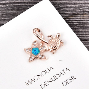 Macro shot of rose gold sea turtle pendant with blue opal star and zircon accents