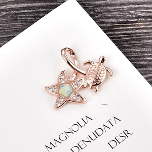 Macro shot of rose gold starfish and turtle pendant with opal and sparkling crystals