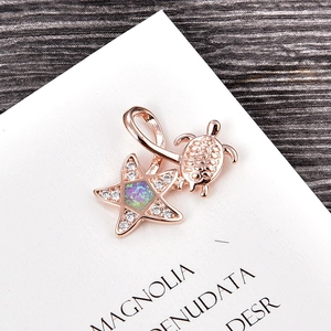 Detail of rose gold starfish and turtle pendant with iridescent opal and zircon stones
