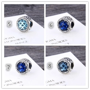 Macro detail of S925 sterling silver charms with sparkling blue zircons and heart patterns