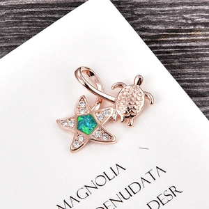 Macro detail of rose gold sea turtle and starfish pendant with green opal and pavé crystals
