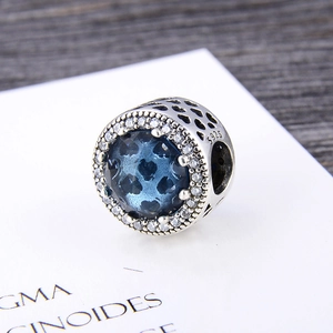 Macro detail of S925 silver charm featuring blue heart gem and pavé cubic zirconia
