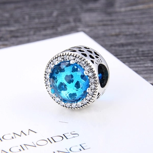 Macro detail of S925 silver charm with blue heart gemstone and sparkling pavé zircons