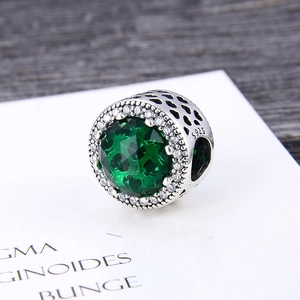 Macro view of S925 sterling silver charm bead with green gemstone and heart cutouts