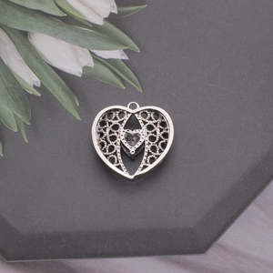 Detailed macro view of heart-shaped silver filigree pendant with centered clear zircon stone