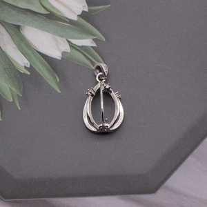 Detailed macro view of a silver teardrop birdcage pendant with small zircon accents