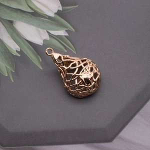 Detail of rose gold heart birdnest pendant with pearl drop on grey textured background