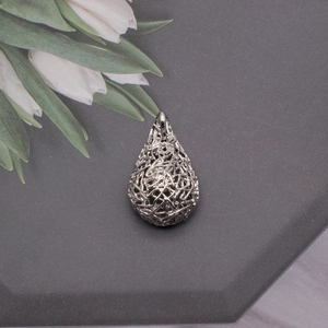 Macro view of teardrop hollow silver pendant with artistic bird nest woven design