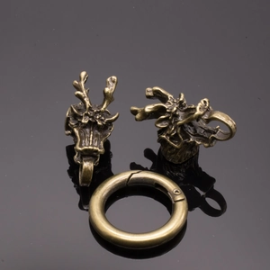 Detailed close-up of brass dragon head jewelry clasp with ornate carving and spring ring