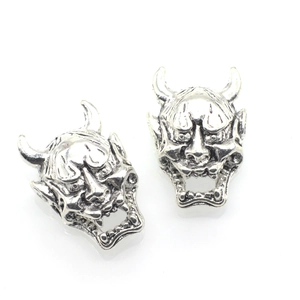 Macro shot of silver Hannya demon charms showing detailed horns and facial textures