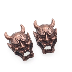 Macro detail of vintage bronze Hannya mask charms for DIY jewelry and paracord beads