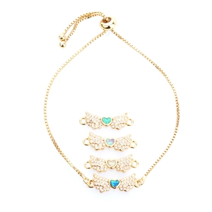 Detail of adjustable gold angel wing bracelets with colorful heart opal and zircons