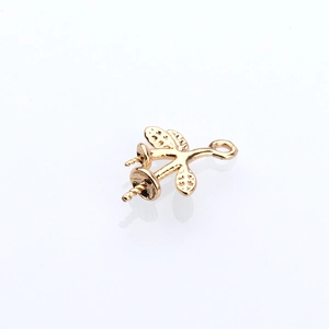 Detailed macro view of golden branch pendant with twin pearl settings and spiral pins