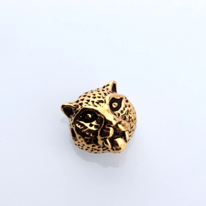 Macro detail of leopard head metal bead with gold plating and black spots for DIY jewelry