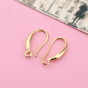 Close-up of golden plated metal DIY earring hooks on a pink decorative background