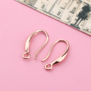 Close-up of rose gold plated earring hooks on pink background for DIY jewelry making