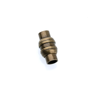Dettaglio di chiusura magnetica cilindrica in bronzo antico con texture ad anelli