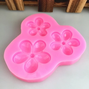 Pink silicone mold featuring three distinct sizes of five-petal flower cavities for baking