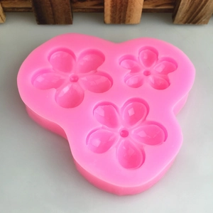 Pink silicone mold with three different sizes of five-petal flower shapes for cake decorating