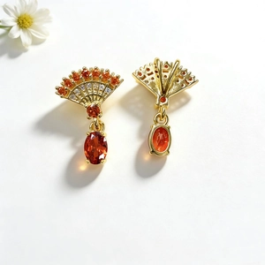 Detail view of gold fan-shaped earrings with orange stones and zircon inlays