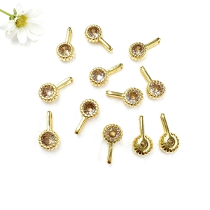 Detailed view of eleven circular gold zircon pendants scattered on a clean white surface
