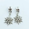 Silver vintage snowflake dangle earrings with minimalist hooks on a light blue background