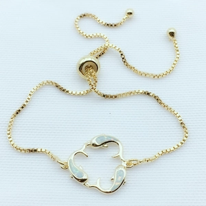 Detail of adjustable golden box chain bracelet featuring three opal-inlaid dolphins