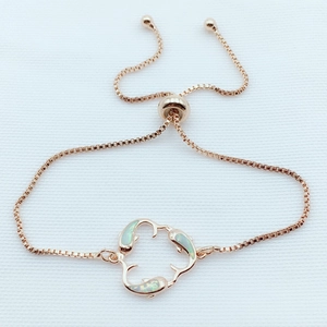 Detail of rose gold dolphin bracelet with adjustable bolo clasp and opal inlays