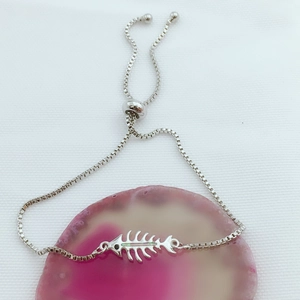 Detalle de pulsera de espina de pescado plateada con ópalo y cadena ajustable de caja